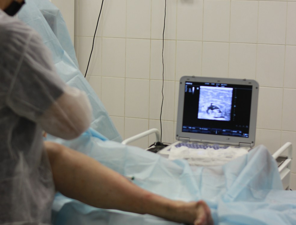 Medical professional administering hyaluronic acid injection to a patient's knee.